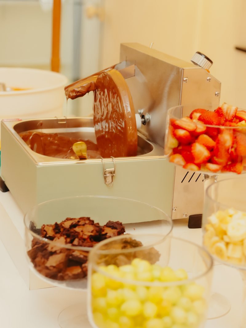 Fonte de chocolate com morangos, uvas e brownie ao lado